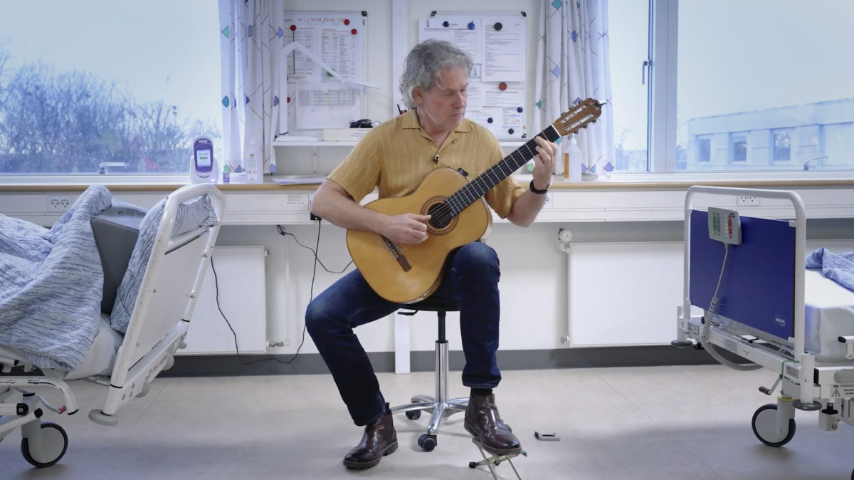 Mand der spiller guitar på en hospitalsstue